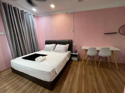a bedroom with a bed and a table with two chairs at AR HOMESTAY & ROOMESTAY in Merlimau
