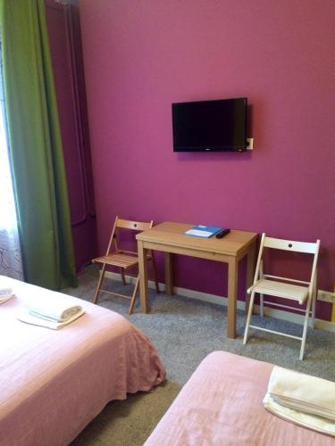 a room with two beds and a table and a tv at Mini-Hotel Spi Zdes in Khabarovsk