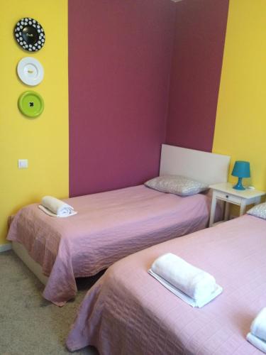 two beds in a room with pink and yellow walls at Mini-Hotel Spi Zdes in Khabarovsk