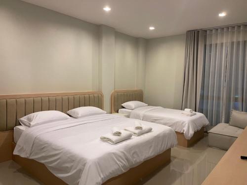 two beds in a hotel room with towels on them at HOMETELhdy in Hat Yai