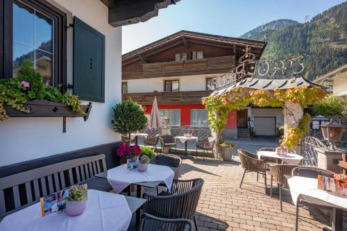 マイヤーホーフェンにあるHotel Jägerhof Mayrhofenのテーブルと椅子のあるパティオと建物