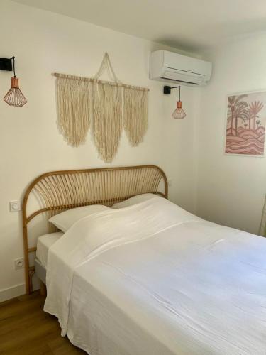 une chambre avec un lit avec des draps blancs et un ventilateur dans l'établissement Casa Dolorès parking, jardin, Gds Buffets 10 min, à Narbonne
