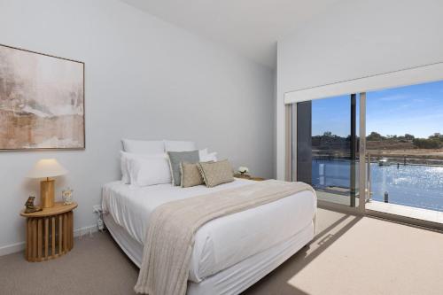 a white bedroom with a bed and a large window at Riverfront Family Home in Mildura in Mildura