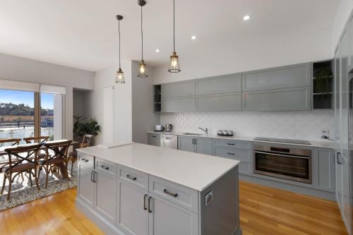 a kitchen with white cabinets and a dining room with a table at Riverfront Family Home in Mildura in Mildura