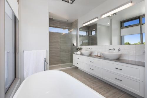 a white bathroom with two sinks and a large mirror at Riverfront Family Home in Mildura in Mildura
