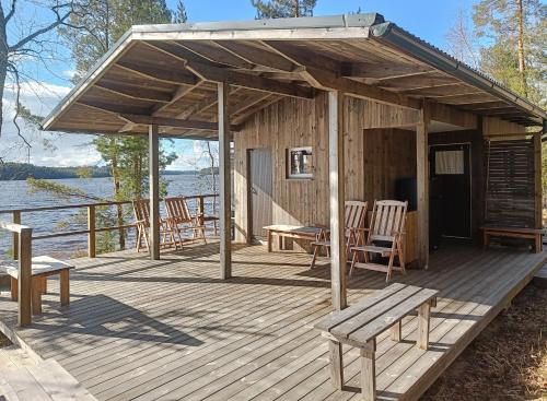 a wooden cabin with chairs and a bench on a deck at Upea miljöö Saimaan rannalla in Joensuu
