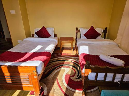 two twin beds in a room with a rug at The Bliss Homestay in Gangtok