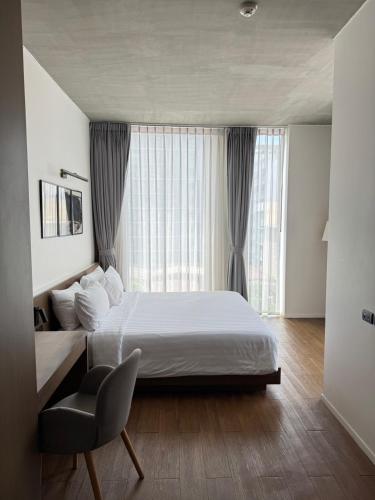 a bedroom with a large bed and a chair at Norma Hotel Sathorn - Formerly T2 Residence Sathorn in Bangkok
