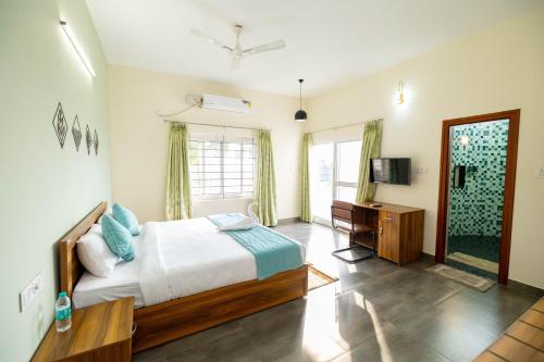 a bedroom with a bed and a desk and a television at Solandis Service Apartment in Manipala