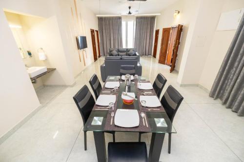 a dining room with a long table and chairs at Solandis Service Apartment in Manipala