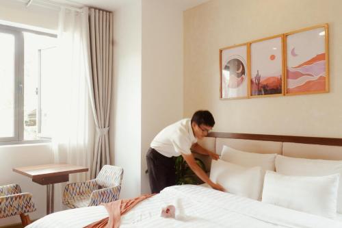 a man putting pillows on a bed in a hotel room at Tasme Dalat Signature in Da Lat