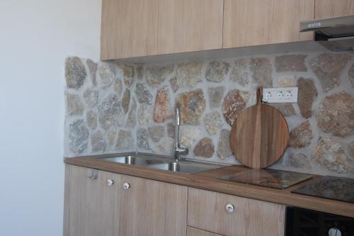 a kitchen with a sink and a stone wall at Kathara Bay Apartments in Faliraki