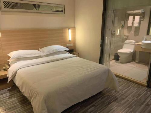 a bedroom with a bed and a bathroom with a shower at City Comfort Inn Yichang Wanda Plaza Yunhe Park in Yichang