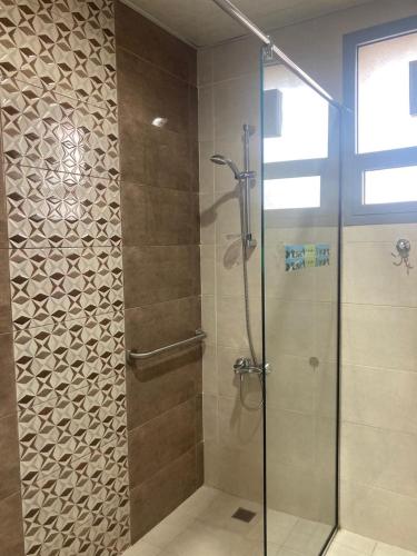 a shower with a glass door in a bathroom at Paris Furnished Apartments - Tabasum Group in Ajman 