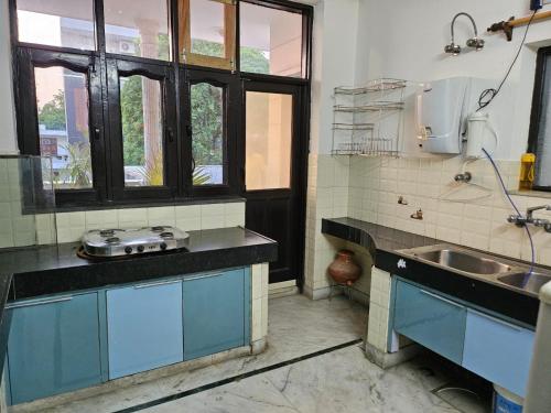 eine Küche mit blauen Schränken und einer Spüle in der Unterkunft Raghuvansh cottage stay in Gurgaon