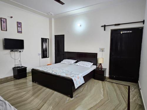 ein Schlafzimmer mit einem Bett und einem Flachbildfernseher in der Unterkunft Raghuvansh cottage stay in Gurgaon