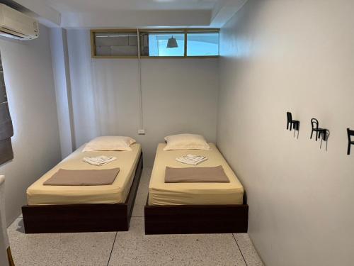 two beds in a small room with a window at Ler Hostel 65 in Chaweng