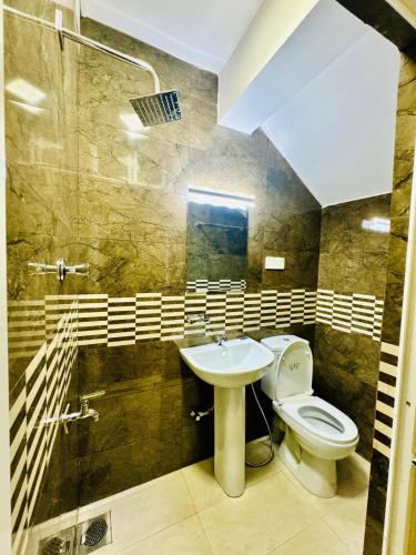 a bathroom with a toilet and a sink and a shower at The Regent Hotel in Colombo