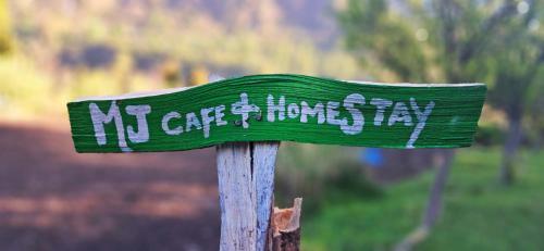 a sign on a wooden pole with graffiti on it at MJ cafe and homestay in Kalgha