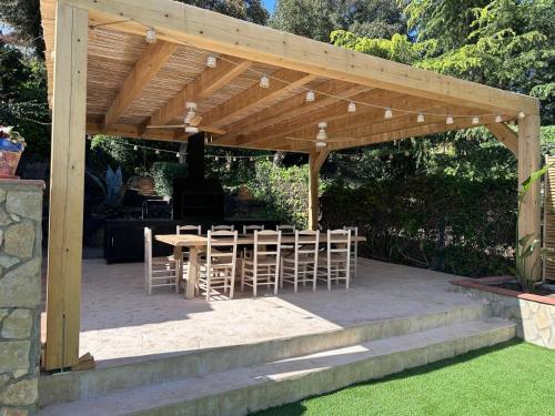 a wooden pergola with a table and chairs under it at Villa Costa Brava in Calonge