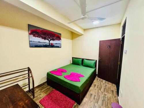 a room with a green bed with pink pillows on it at The Regent Hotel in Colombo