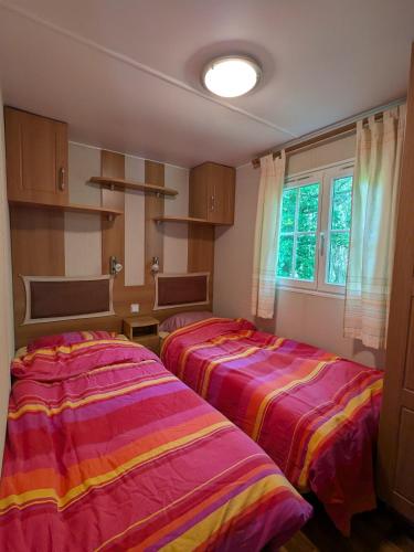 deux lits dans une chambre avec une fenêtre dans l'établissement Mobile home tout confort dans un camping 4 étoiles, à Pont-Aven