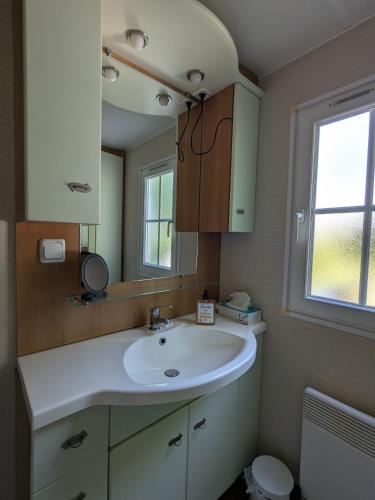 une salle de bain avec un lavabo et un miroir dans l'établissement Mobile home tout confort dans un camping 4 étoiles, à Pont-Aven