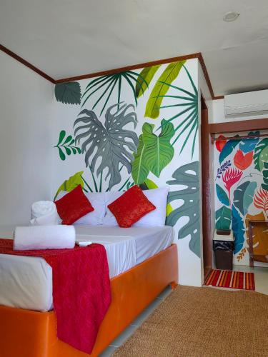 a room with a bed with a tropical mural on the wall at Orange Pearl Beach Resort in El Nido
