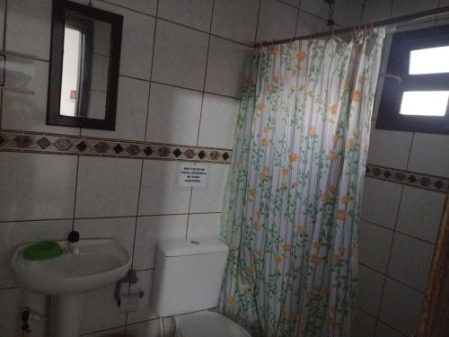 a bathroom with a toilet and a sink and a shower curtain at Cidreira-Salinas Casinha in Cidreira