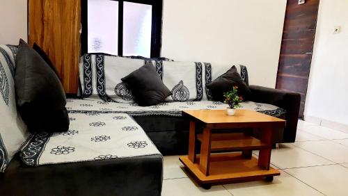 a living room with a black couch and a table at Hotel Season in Ahmedabad
