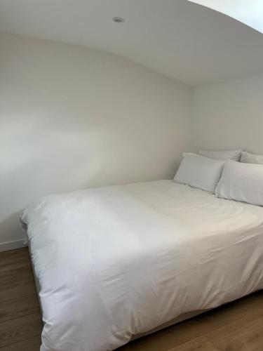 un lit blanc avec des draps et des oreillers blancs dans l'établissement Le perchoir toulousain, à Toulouse