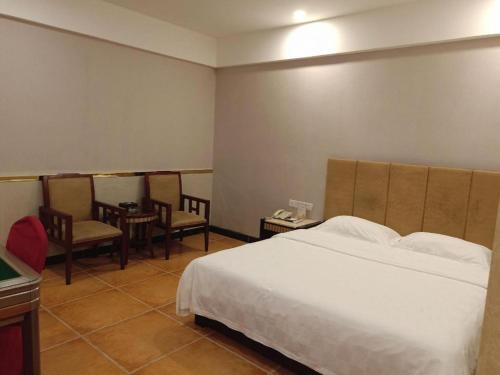 a bedroom with a bed and a table and chairs at Zhongshan Hui Quan Hotel in Zhongshan