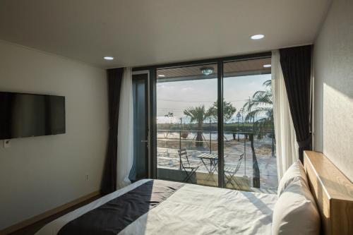 J Raum Resort في سيوجويبو: غرفة نوم بسرير ونافذة زجاجية كبيرة