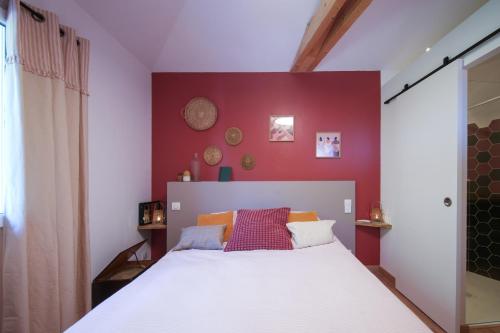 une chambre avec un lit blanc avec un mur rouge dans l'établissement Chambre cosy avec entrée privée, à Bayonne