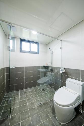 a bathroom with a toilet and a glass shower at J Raum Resort in Seogwipo