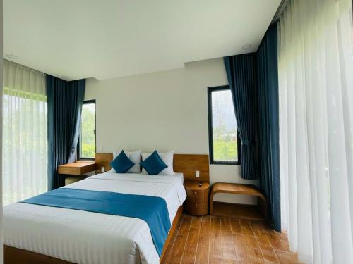 a bedroom with a large bed and two windows at Baisao Villa in Phú Quốc