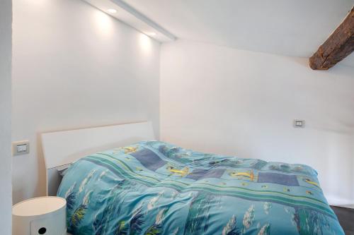 a white bedroom with a bed with a blue comforter at Mansarda a Ca' Leuscc in Montagna in Valtellina