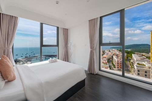 a bedroom with a white bed and large windows at La isla Apartments & Villas - Sea View & Fireworks Phu Quoc in Phu Quoc