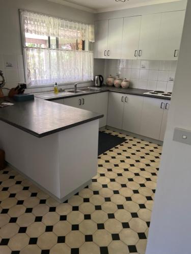 a kitchen with white cabinets and a checkered floor at Quiet court easy stroll shops 500 metres from Centro in Mildura