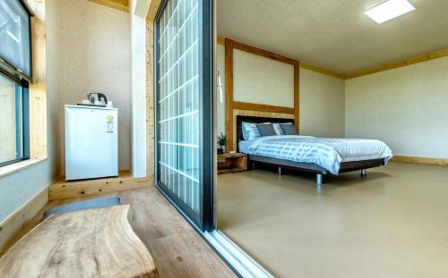 um quarto com uma cama e um pequeno frigorífico em Bada Maru Pension em Seogwipo