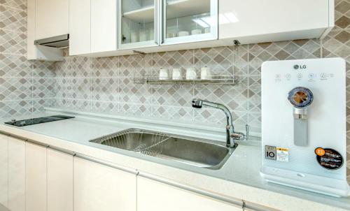 a kitchen with a sink and a microwave at Bada Maru Pension in Seogwipo