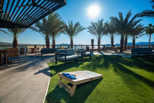 a patio with tables and chairs and palm trees at The Nautical Beachfront Resort in Lake Havasu City