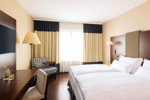 a hotel room with a bed and a desk at NH Vienna Airport Conference Center in Schwechat