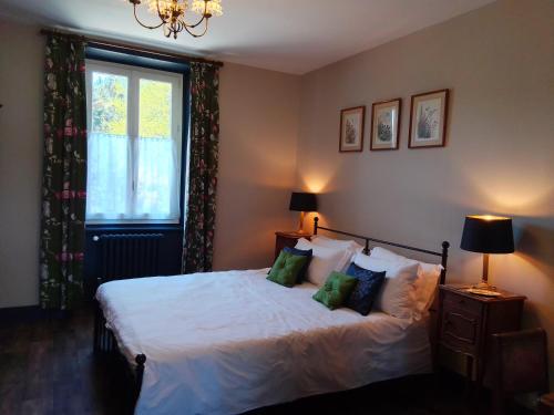 a bedroom with a bed with green pillows and a window at L'ancienne Gendarmerie in Saint-Laurent-sur-Gorre