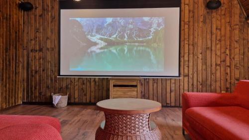 a living room with a table and a large screen at UMANI Retreat in Buşteni