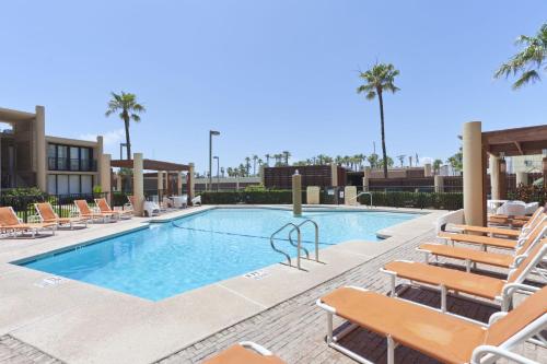 a swimming pool with chaise lounges and chairs at Sea Vista in South Padre Island
