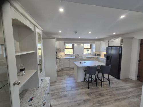 a kitchen with white cabinets and a black refrigerator at Donegal holiday home in Donegal
