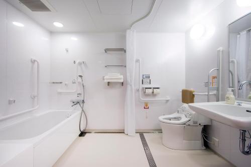 a white bathroom with a sink and a toilet at Karaksa Hotel Osaka Namba in Osaka