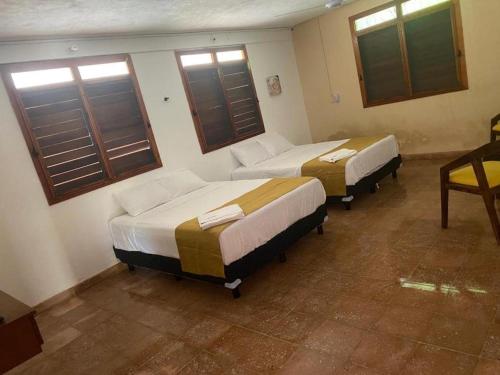 two beds in a room with windows at Villa Chic in Chicxulub