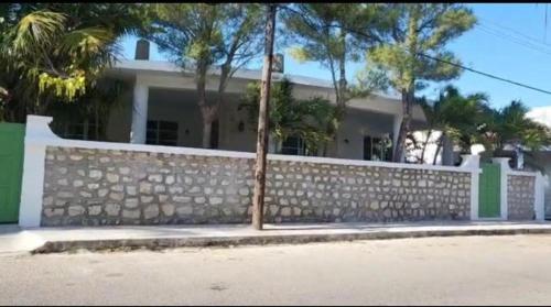 a house with a stone fence and palm trees at Villa Chic in Chicxulub